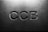 Letters 'CCB' are engraved in a concrete or stone surface, with subtle shadows creating a three-dimensional effect. The lighting is soft, emphasizing the texture of the material.