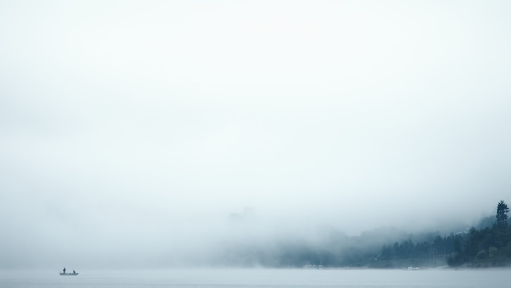 a foggy lake with a boat in the distance