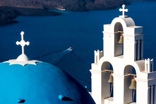 white cathedral and boat on seat in Santorini Greece