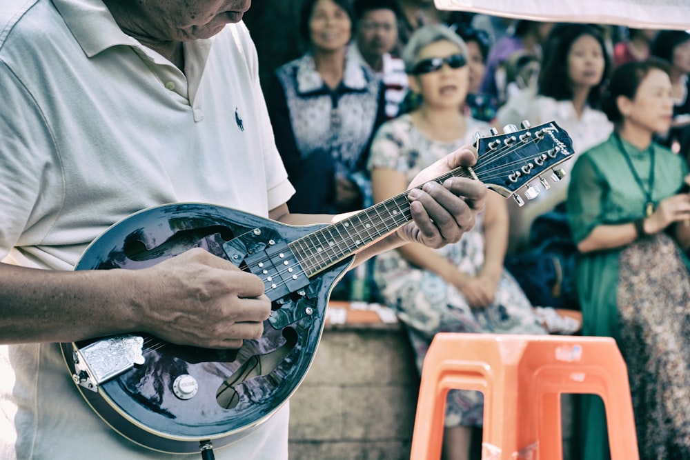 man playing string instrument near croud