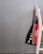 Two tote bags are hanging on the back of a white wooden chair against a plain gray wall. One bag is black with white text and the other is orange with white text.