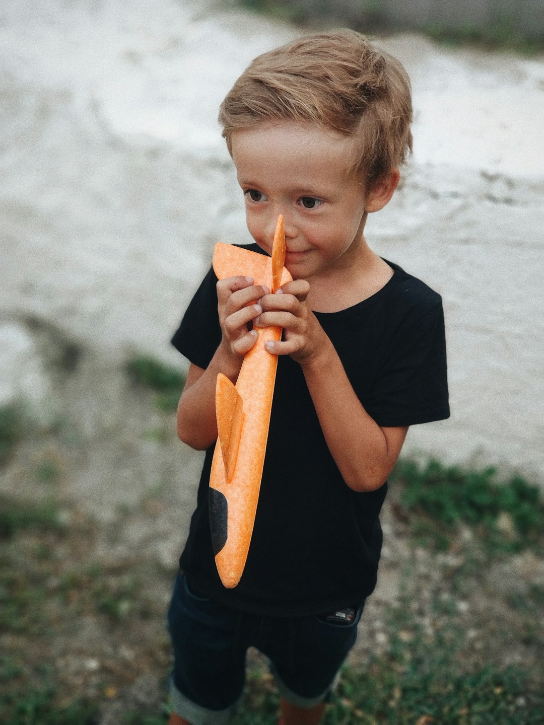 boy holding orange plastic plane toy
