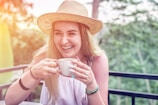 An attractive single woman laughing while holding a coffee cup.