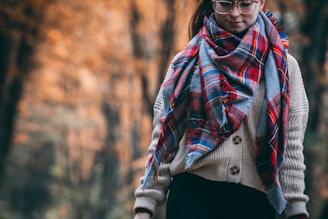 Warm wool scarf wrapped snugly around a person walking through autumn leaves.