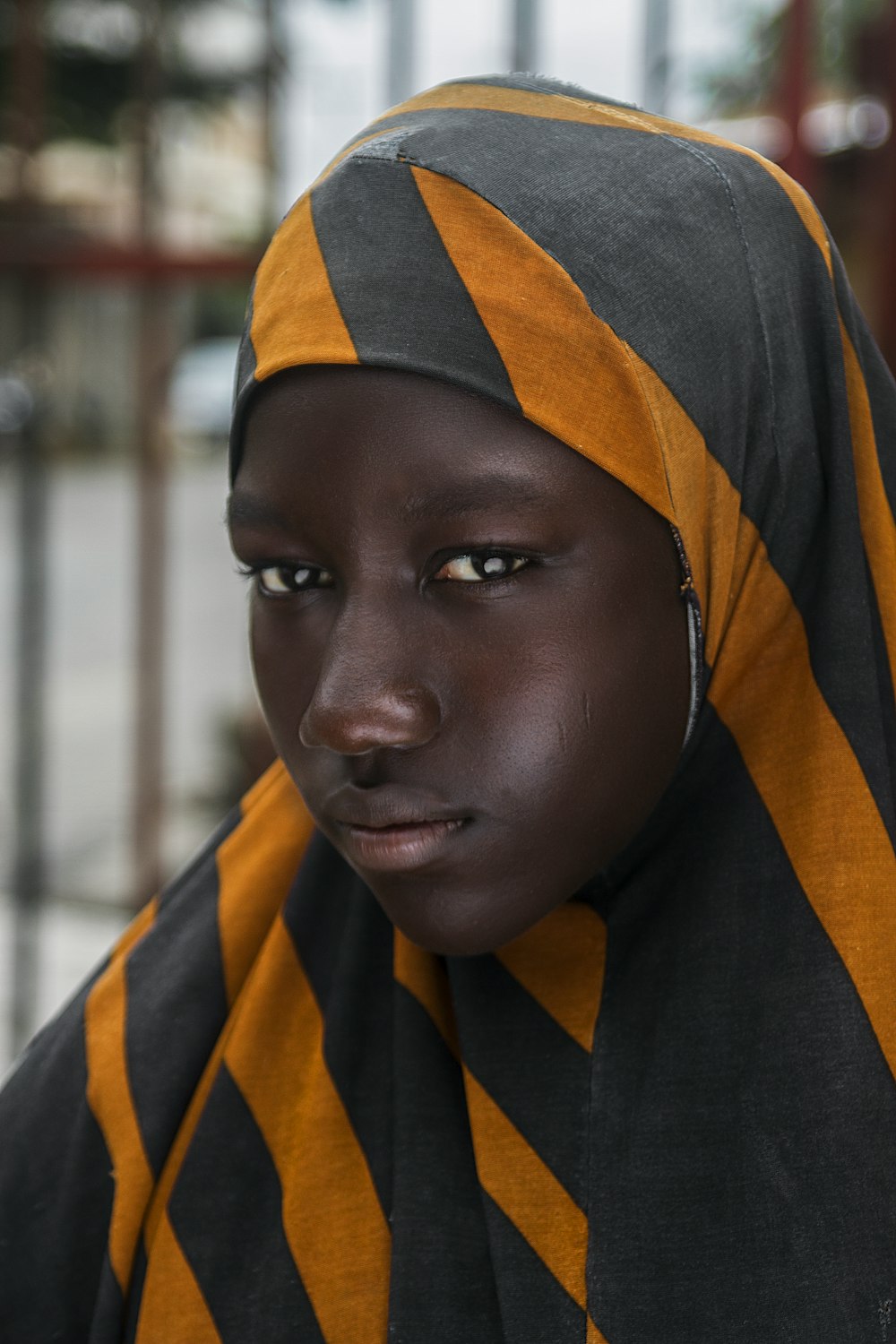 Muchacha en pañuelo de cabeza a rayas negras y naranjas en fotografía de enfoque selectivo