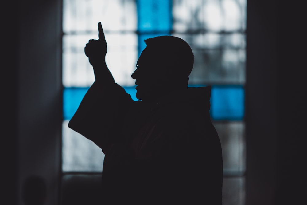 silhouette of man standing near stained glass window