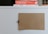 A beige piece of cardboard is clipped to a white board using a black binder clip. In the background, a stack of books features prominently, with visible titles including 'Script Fonts', 'TYPO', and 'SKETCH'. The arrangement appears organized and minimalist.