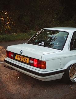 A shiny white BMW 3 Series cruising through the vibrant streets of London with iconic red buses in the background
