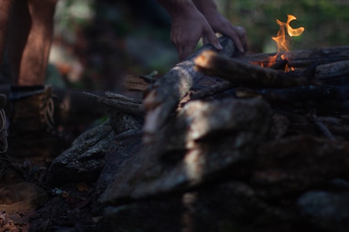 Close-up of hands carefully extinguishing a small campfire to prevent wildfires.