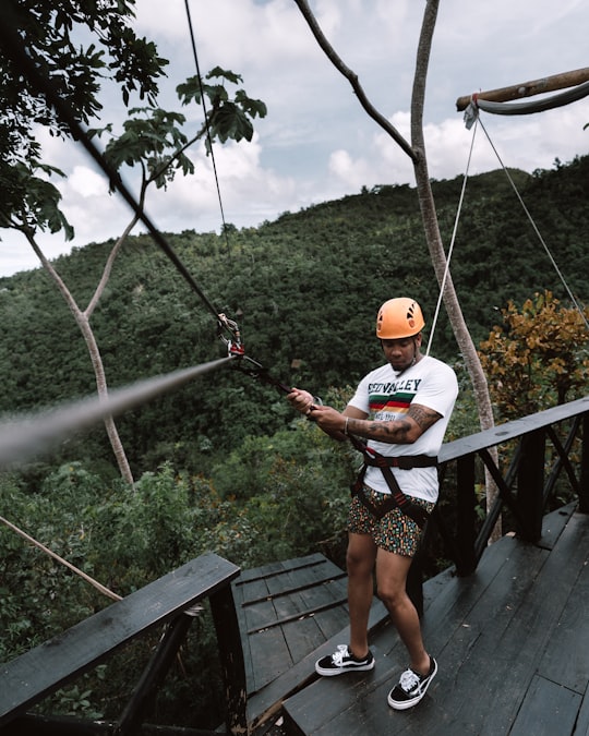 man standing on black stair holding zipline in Samaná Province Dominican Republic