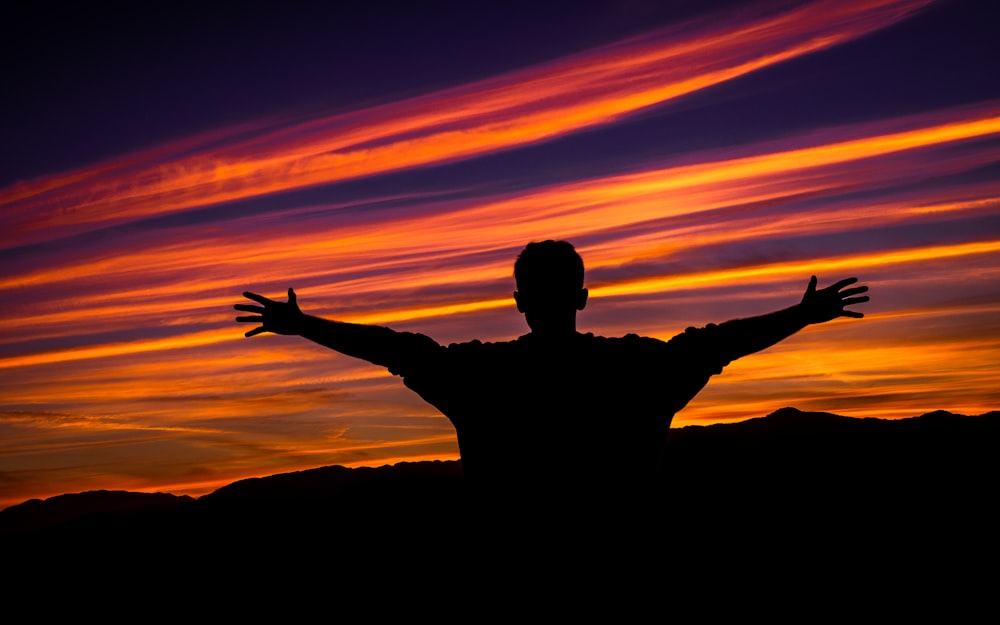 silhouette of man raising hands sideward