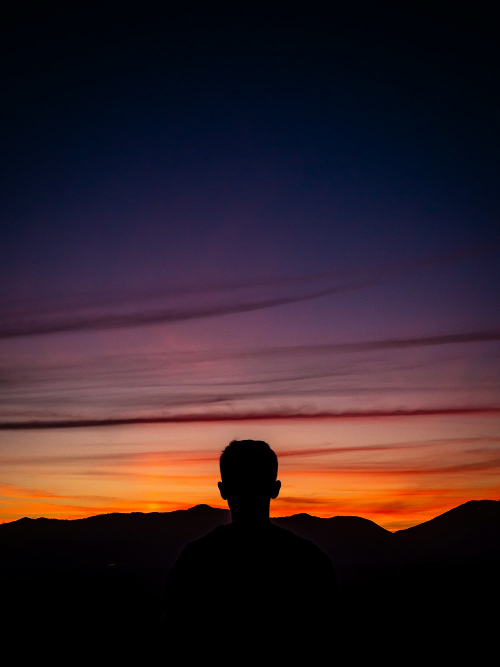 silhouette of man standing with mountain on horizon