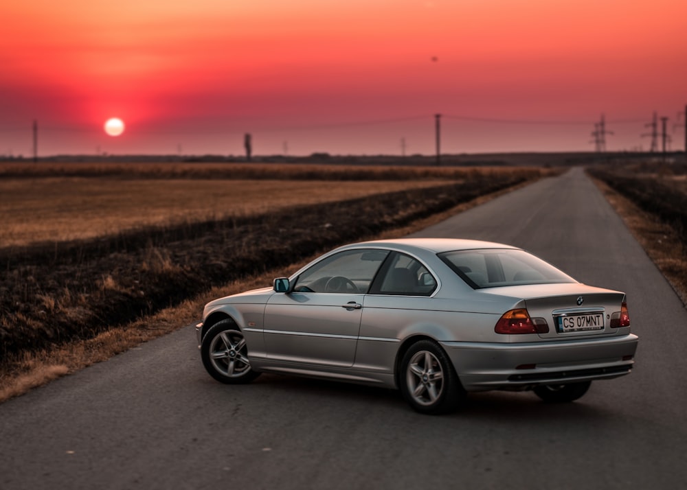 silver coupe in the middle of road near field