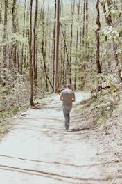 A man walking along a sunlit path surrounded by trees, symbolizing a journey of faith.
