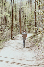 A man walking from shadowed woods into a bright golden sunrise, symbolizing new beginnings.