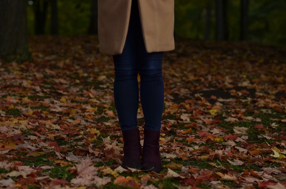 person walking on ground surrounded by dried leaves