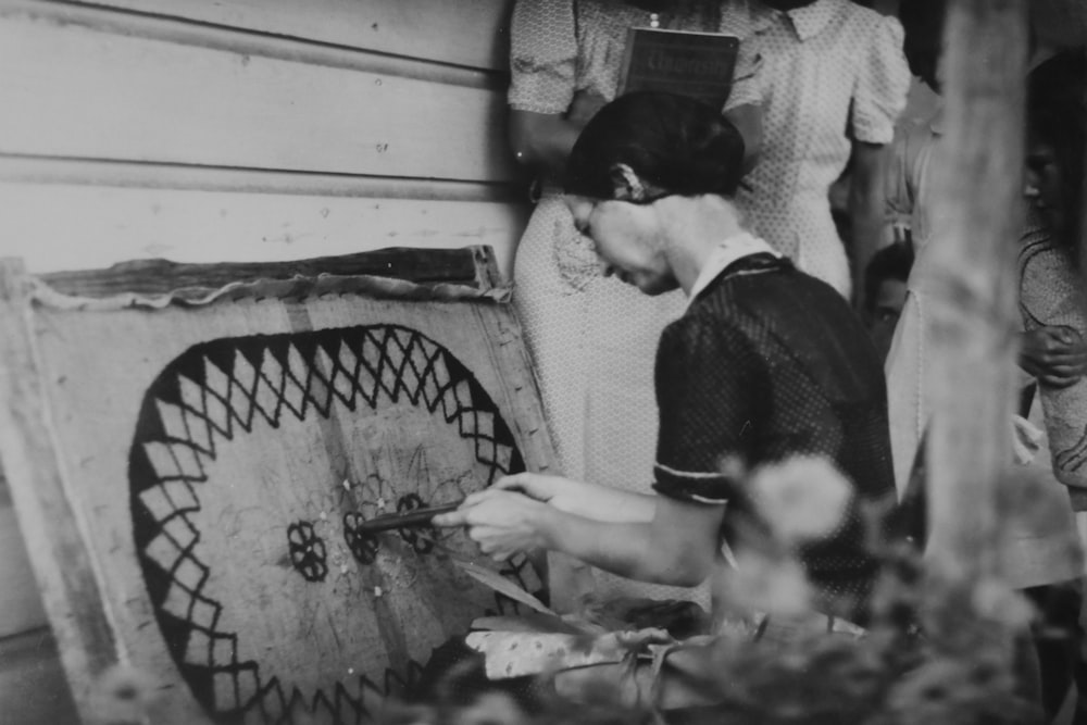 grayscale photography of woman in front of fabric