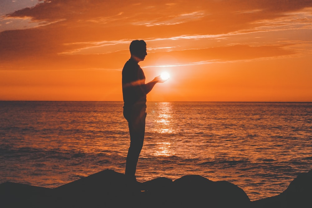 silhouette of man standing near sea shore