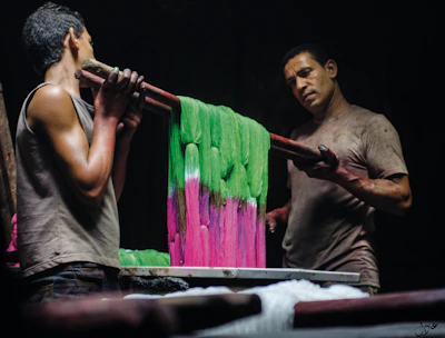 Artisan hand-dyeing vibrant cloth using Acacia Confusa root bark in a sunlit workshop.