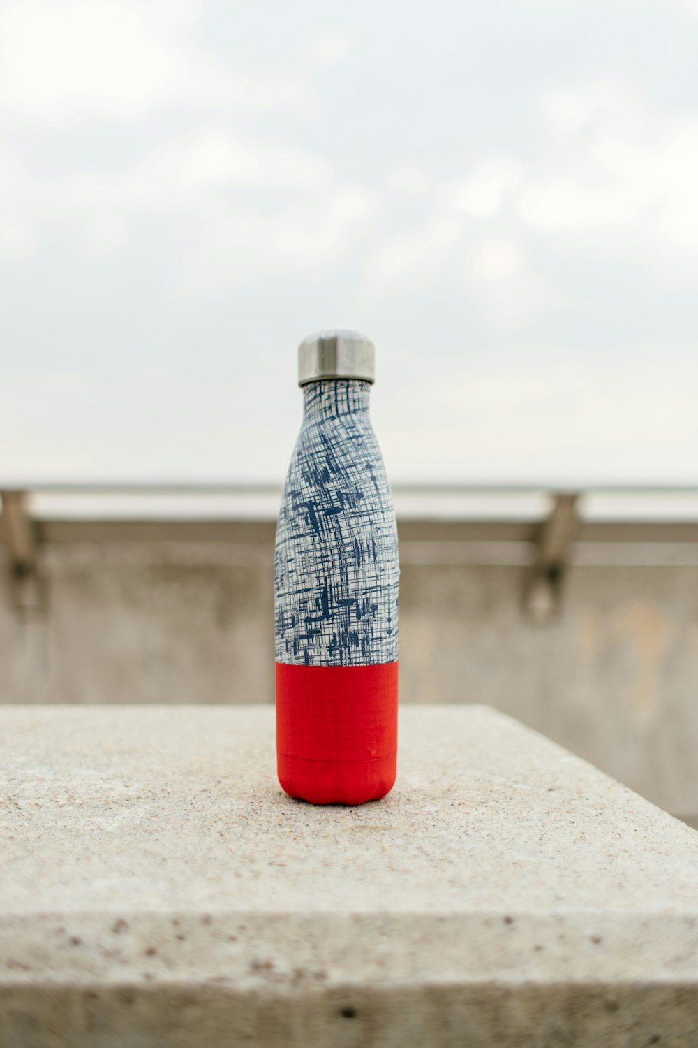 bouteille grise et rouge sur surface en béton blanc