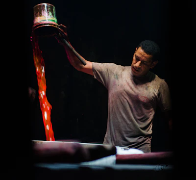 A worker stirring paint chemicals in a large mixing vat.