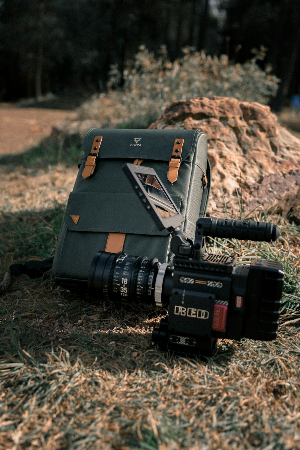 black video camera and gray bag laying on grass