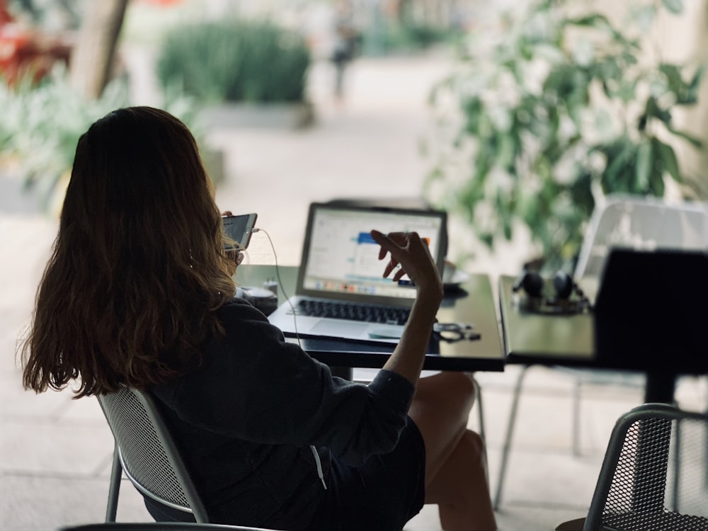 Frau sitzt auf Stuhl vor Tisch mit Laptop