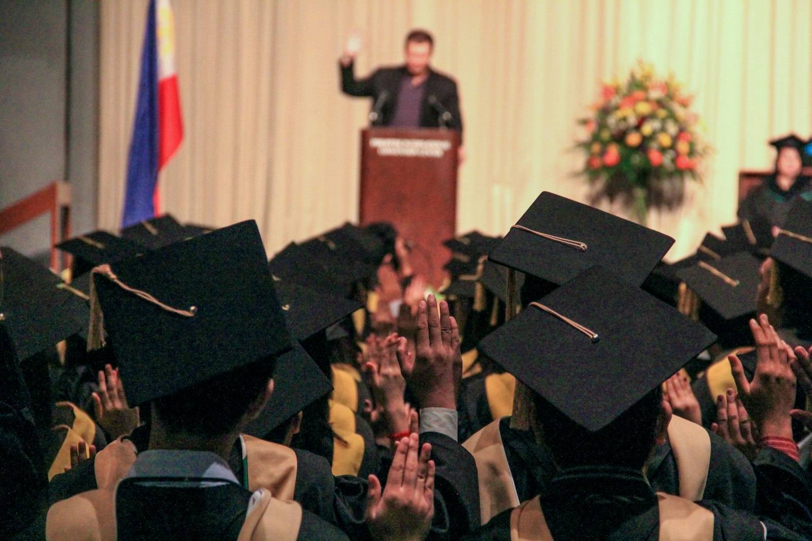 Graduates in caps raising their hands during a commencement ceremony in the Philippines