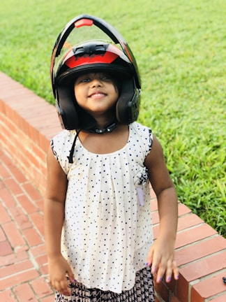 A child wearing a brightly colored safety helmet, smiling on a sunny day.