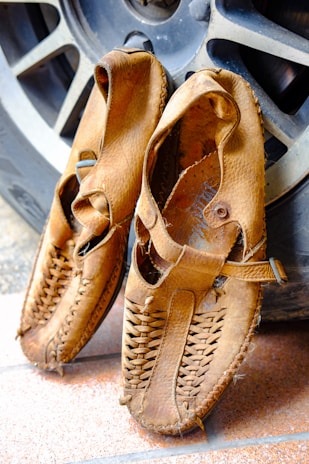 Handcrafted Kolhapuri sandals resting on a rustic wooden floor.