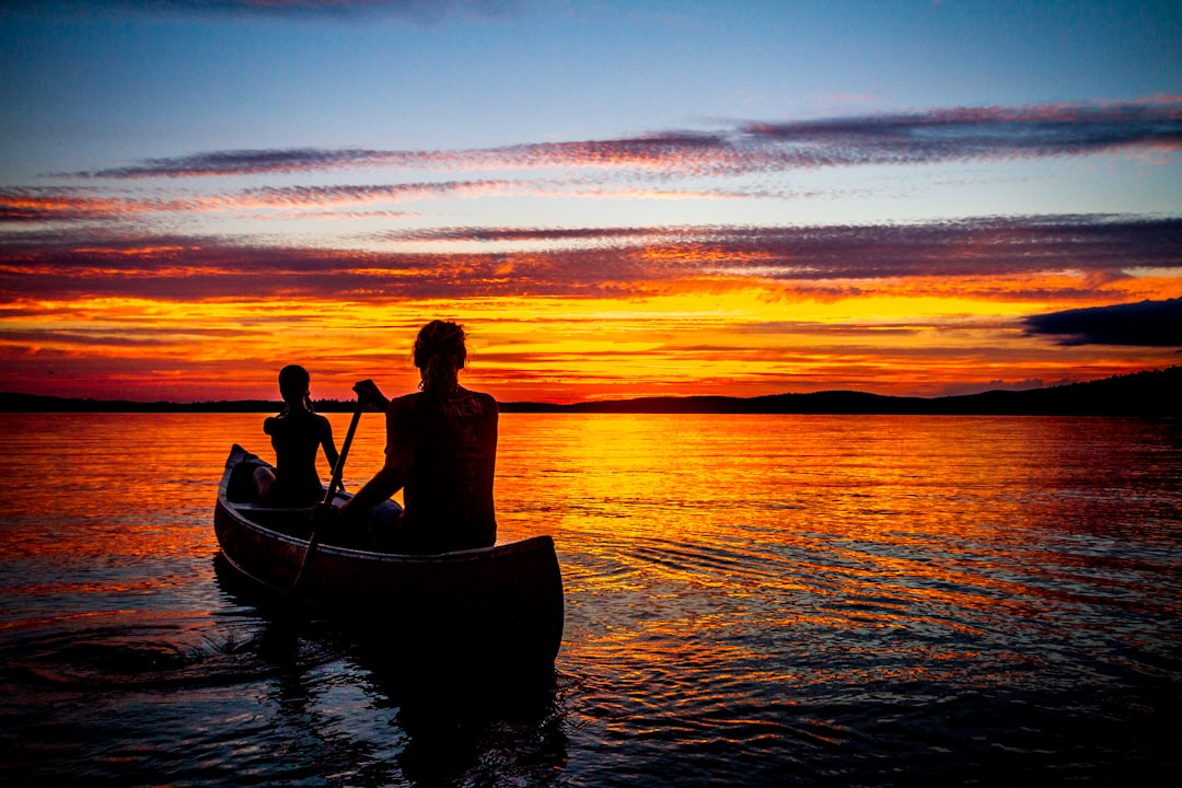 two person rowing boat on body of water during daytime