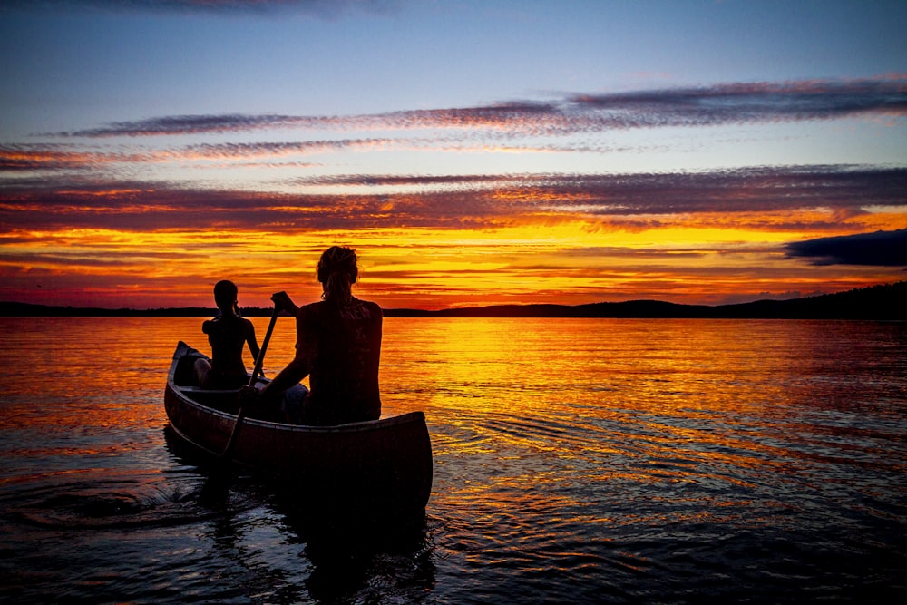 two person rowing boat on body of water during daytime