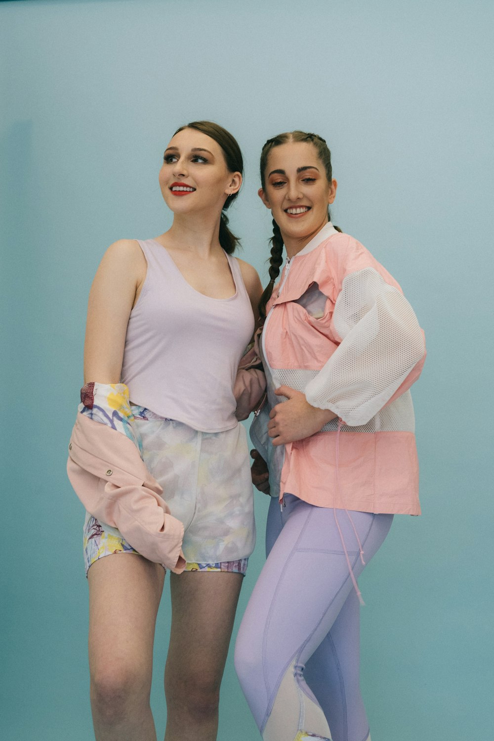 two women standing beside green wall