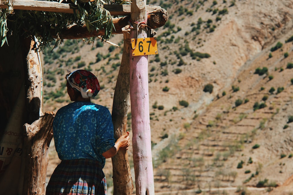 woman in blue blouse holding on house post