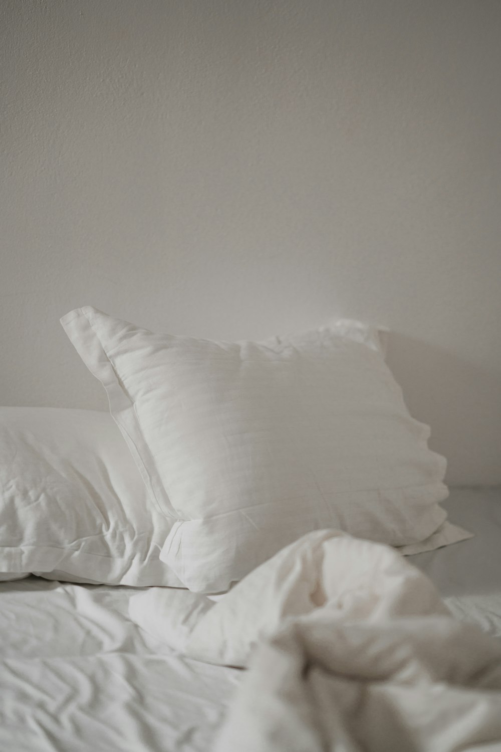 cuscino da letto bianco contro muro bianco