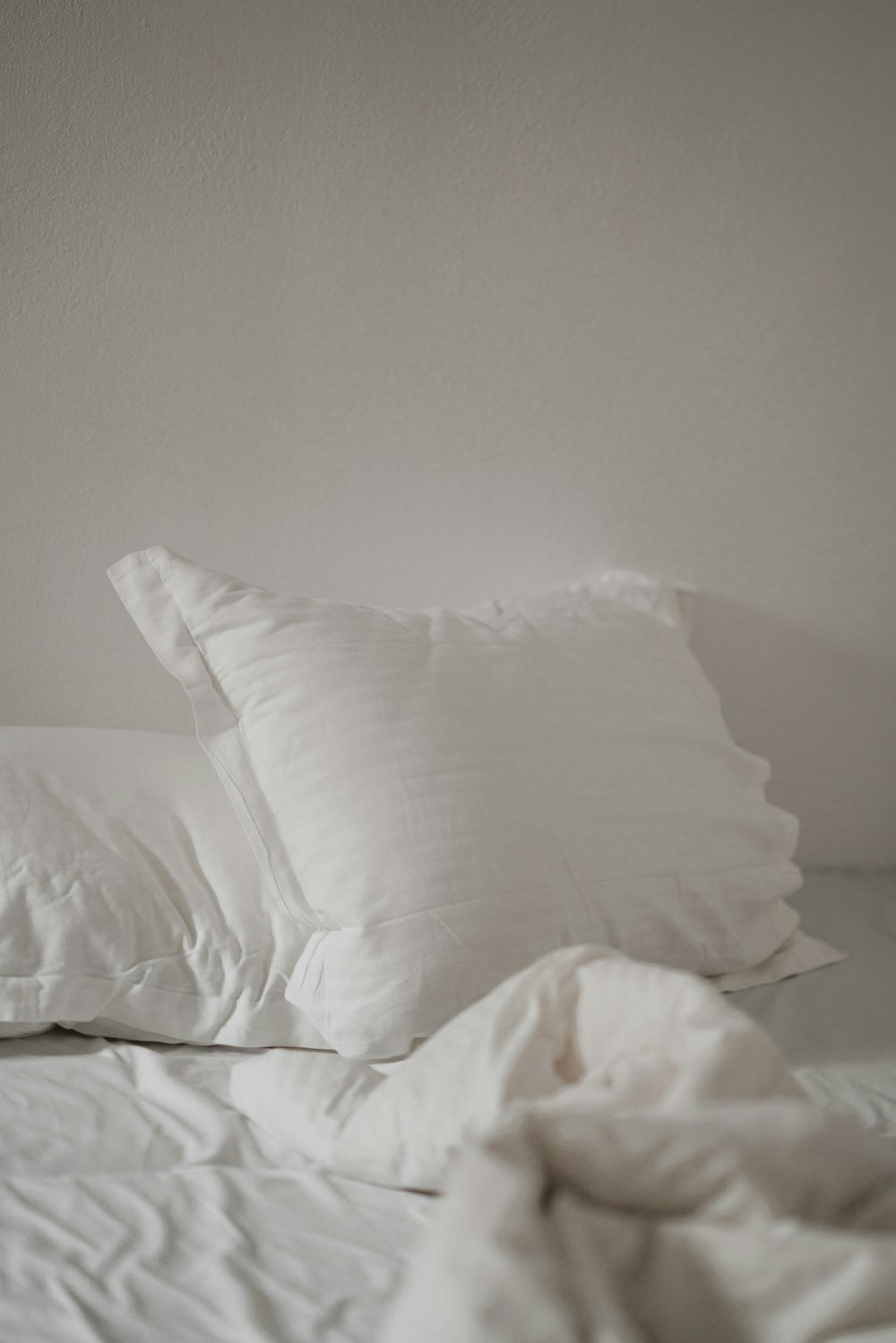 travesseiro de cama branco contra parede branca