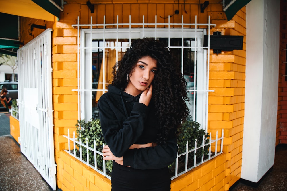woman in black pullover hoodie standing in front of window