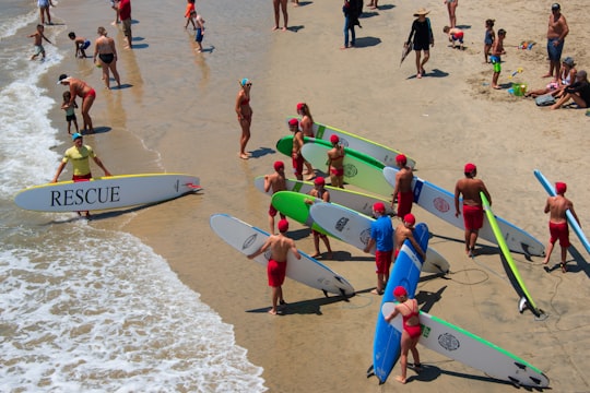 people holding surfing boards on seashore in Huntington Beach United States