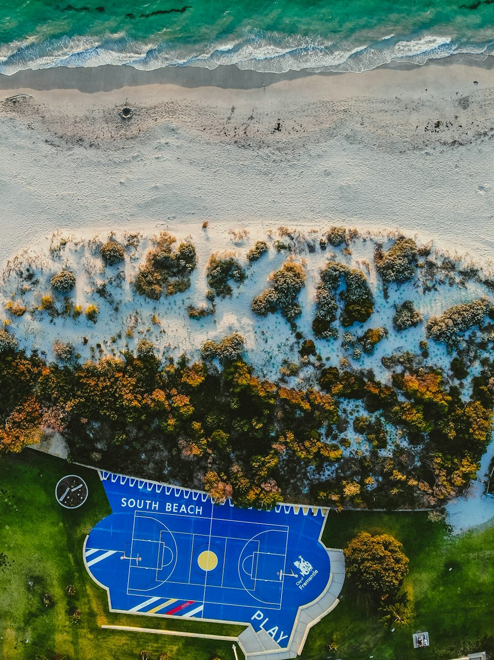 an aerial view of a beach with a basketball court