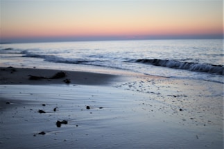 A serene beach scene with smooth sea glass scattered on the sand under soft sunlight.
