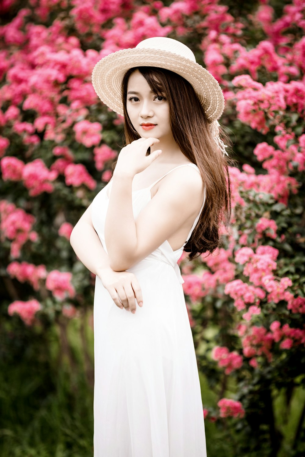 donna che indossa il vestito in piedi accanto ai fiori rosa