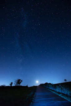 Serene image of a person walking on a path under a starry sky with soft moonlight