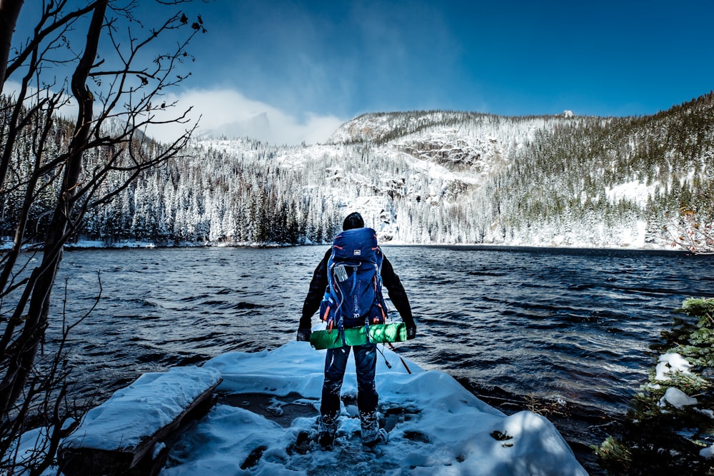 man with backpack in front of body of water