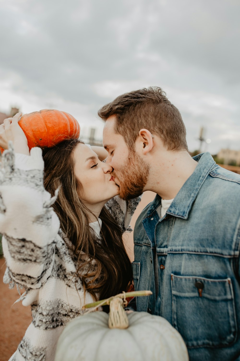 homem e mulher se beijando segurando abóbora durante o dia