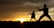 Silhouettes of two people practicing martial arts poses against a stunning sunset backdrop, with the sun peeking over the horizon and casting a warm glow.