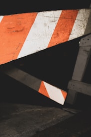 Wooden barricades with diagonal orange and white stripes are positioned against a dark background, suggesting a restricted area or construction zone.