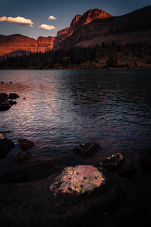 Golden hour light bathing a serene mountain lake with a lone traveler gazing at the horizon