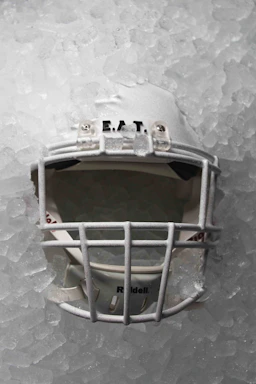 A sleek ice hockey helmet resting on a polished wooden bench under bright arena lights.