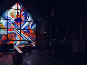 A warm, inviting church interior bathed in soft orange light highlighting stained glass windows.