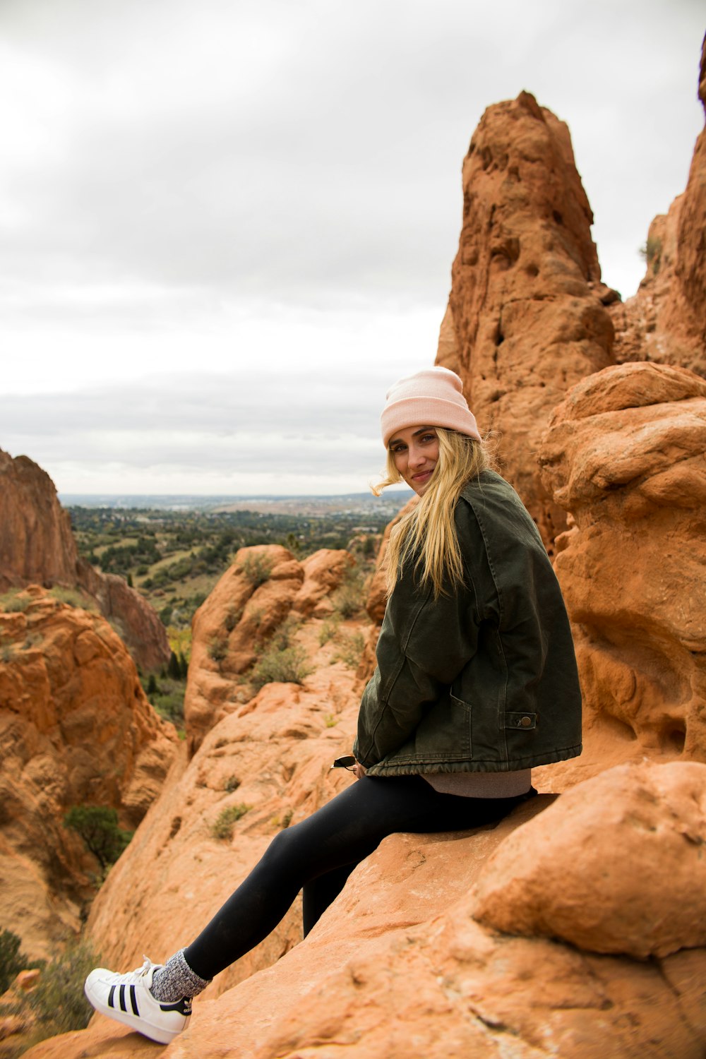 woman in black denim jacket sitting on rock formation during daytime